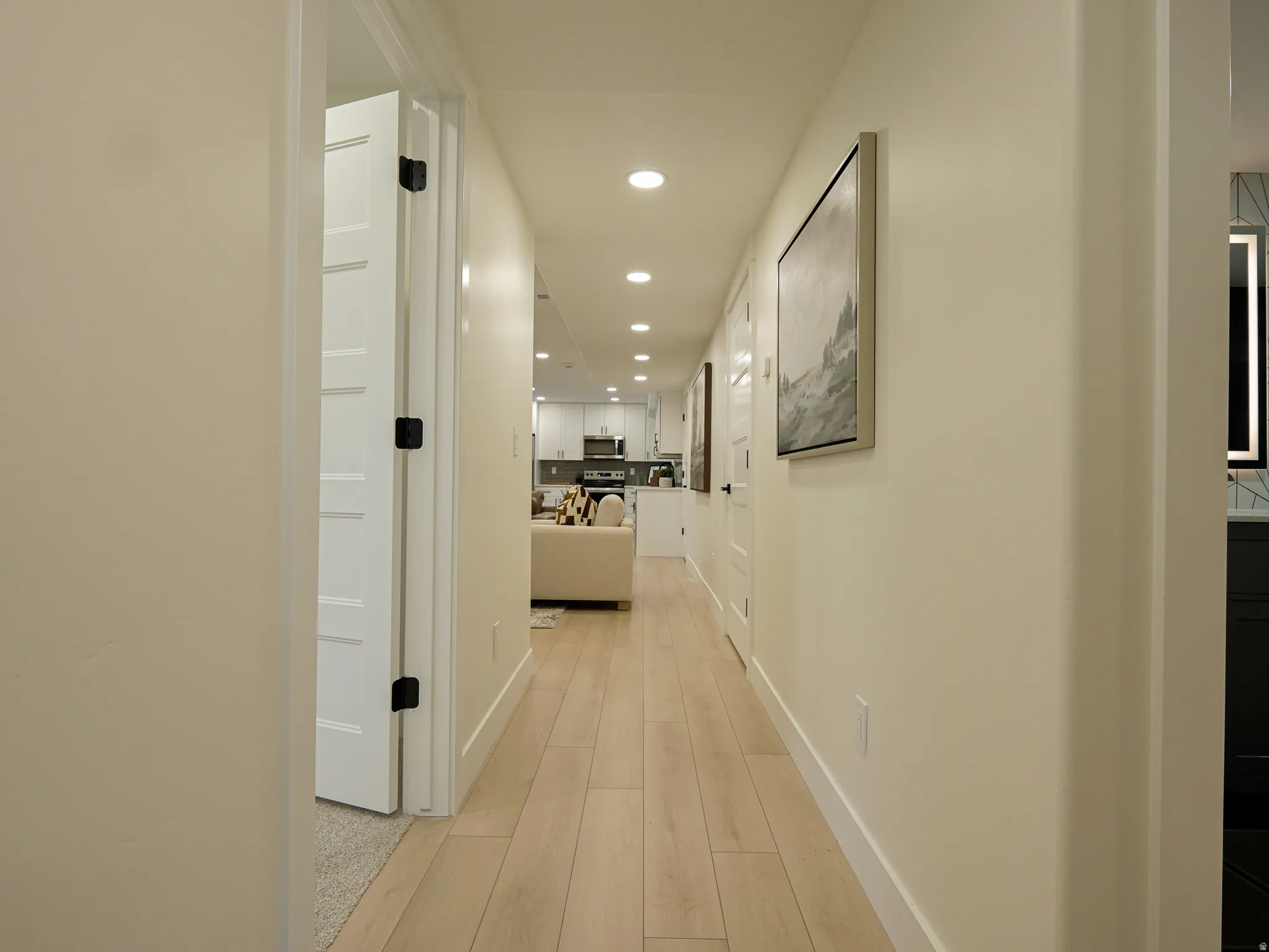 Hallway featuring light wood-finish flooring, recessed lighting, and white baseboards