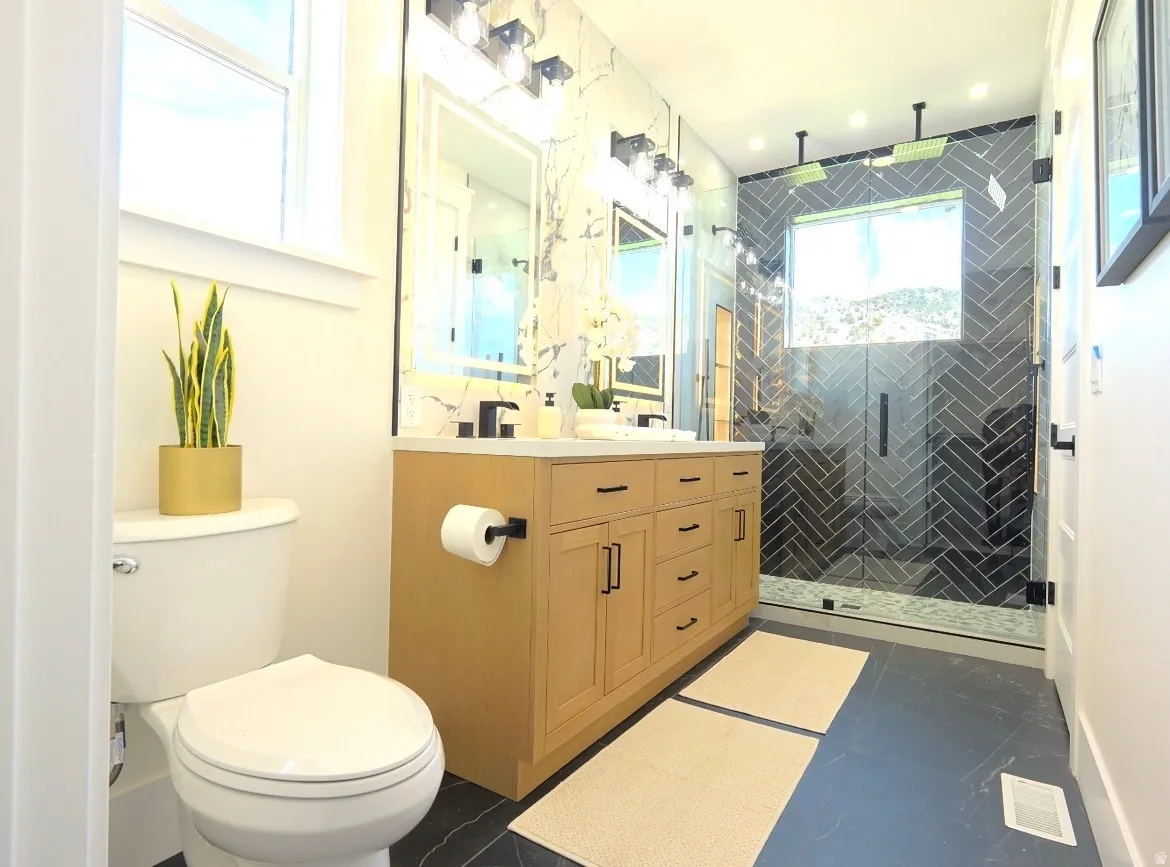 Bathroom featuring a dual vanity with light wood cabinetry, a white countertop, and matte black hardware