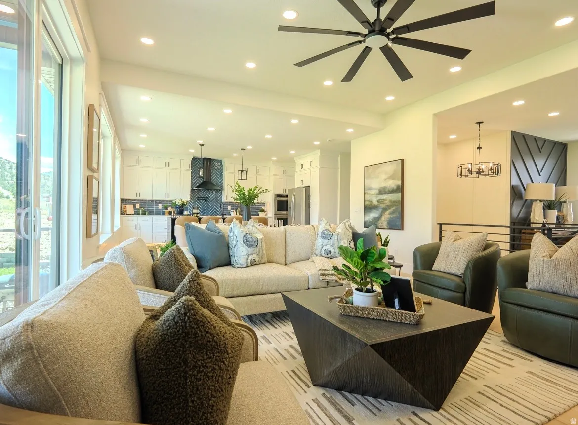 Open-concept living area featuring an expansive kitchen with white cabinetry and a patterned tile backsplash, recessed lighting, a modern ceiling fan, and sliding glass doors
