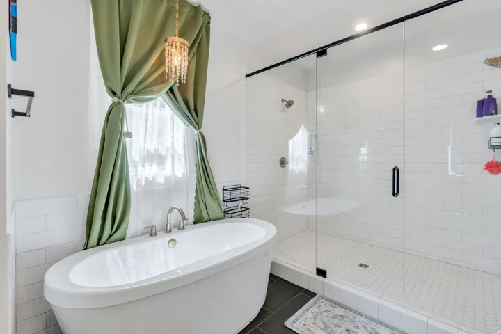 Full bath with tile walls, a freestanding bath, a shower stall, dark tile patterned flooring, and wainscoting