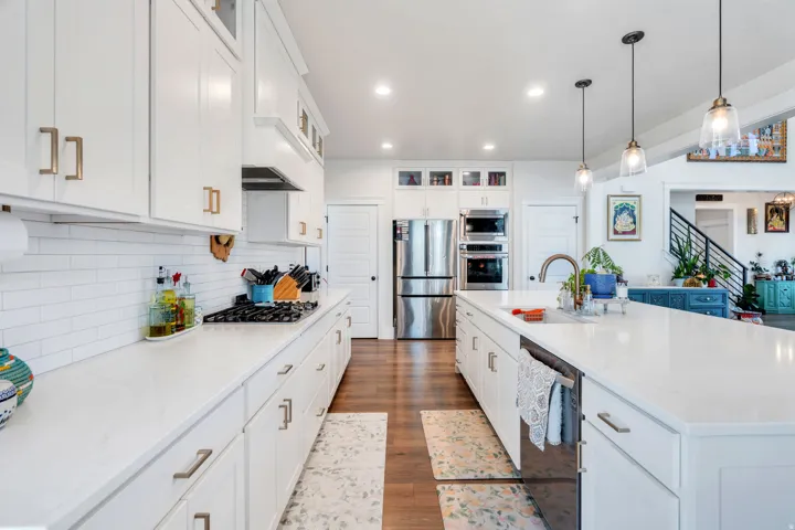 Kitchen featuring glass fronted cabinets, dark wood-type flooring, white cabinetry, stainless steel appliances, and light stone countertops