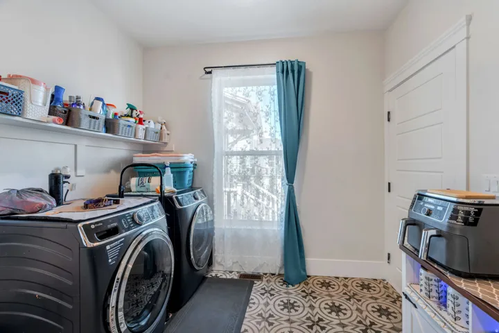 Laundry room with independent washer and dryer and light tile patterned floors