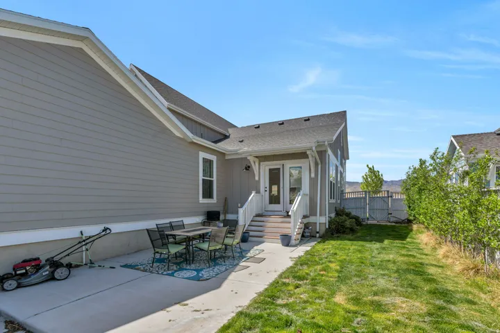 Rear view of property featuring a patio, board and batten siding, roof with shingles, and outdoor dining space