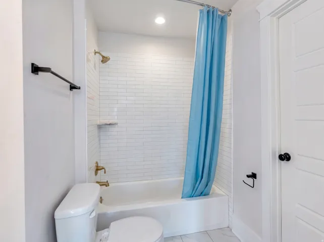 White subway tile shower surround with integrated shelving and brass fixtures