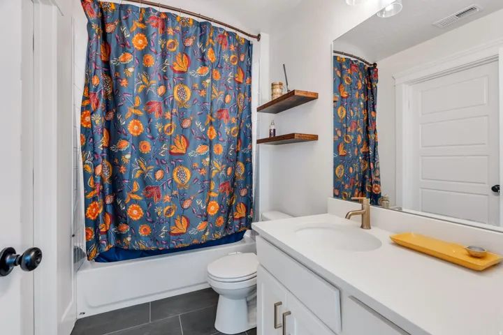 Full bath with vanity, shower / tub combo, and dark tile patterned flooring