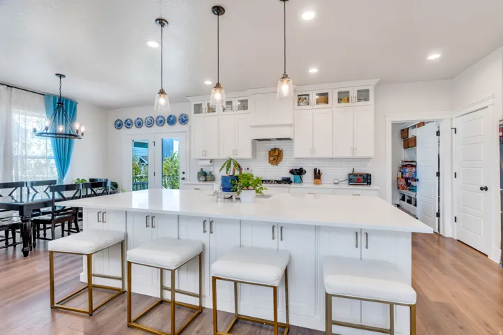 Kitchen featuring a breakfast bar area, white cabinets, a large island, and glass fronted cabinets
