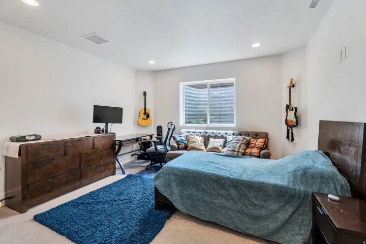Carpeted bedroom with an office area and recessed lighting