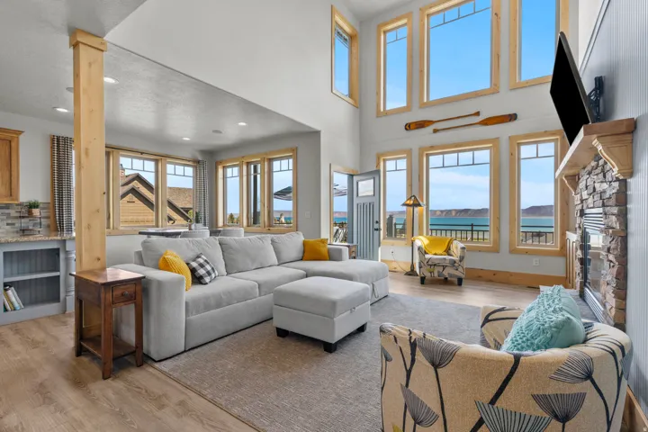 Spacious living area featuring 2-story ceilings, wood-trim, and a stone-faced, gas fireplace with a wood mantel