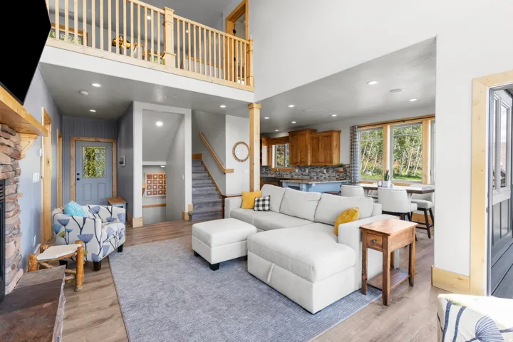 Open-concept living area featuring wood-finish trim, gas fireplace, and an upper-level den area, open with balcony over looking.