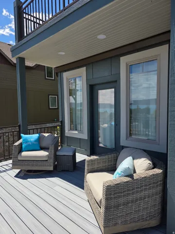 Still part of the main deck that faces the Bear Lake but the south view showinf a separate door to primary bedroom. featuring composite decking, a balcony above with black metal railing, and recessed ceiling lighting