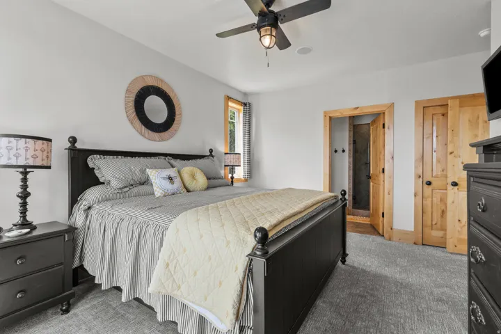 Bedroom featuring textured carpeting, a ceiling fan with integrated lighting, natural wood door frames, and a ceiling light/fan combo.