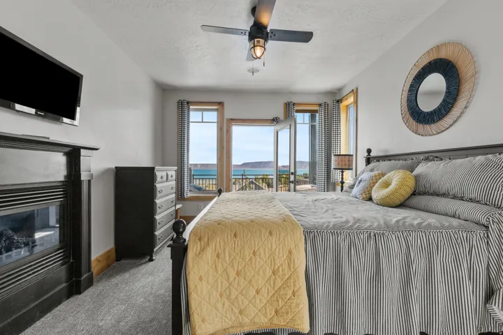 Primary off great room, Bedroom featuring a built-in fireplace, ceiling fan with integrated lighting, and direct access to an outdoor balcony.