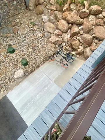 Exterior stone and gravel landscape, concrete walkway, and composite decking.  Shows you where the propane tank is buried underground on the south side with dedicated pad.