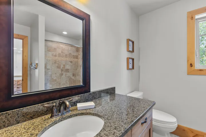 1/2 Bathroom featuring a granite countertop vanity with oil-rubbed bronze fixtures. Easy access from great room and door to back patio.