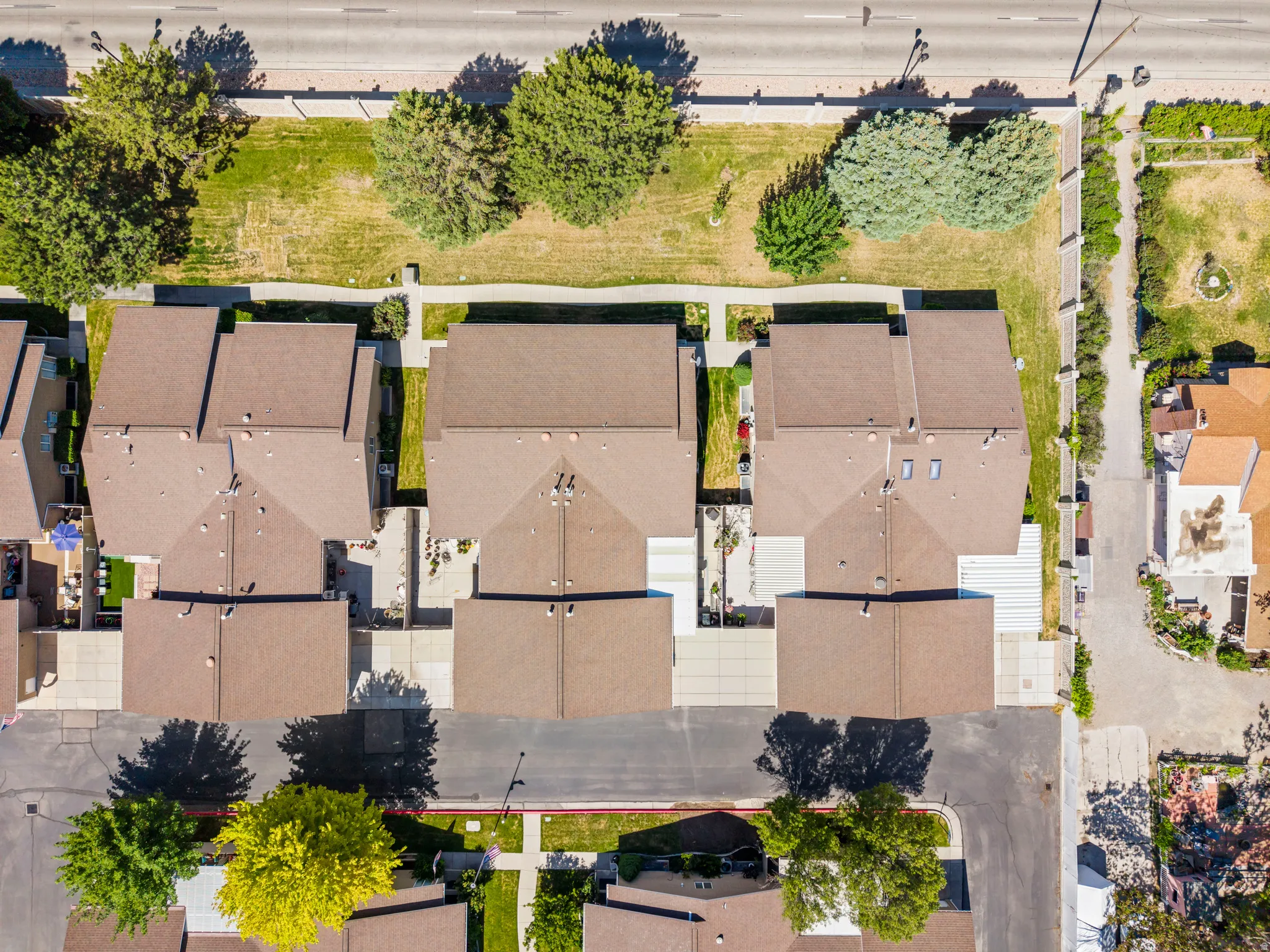 Aerial perspective showcasing a residential street with multiple properties, each featuring brown shingle roofing and individual concrete driveways