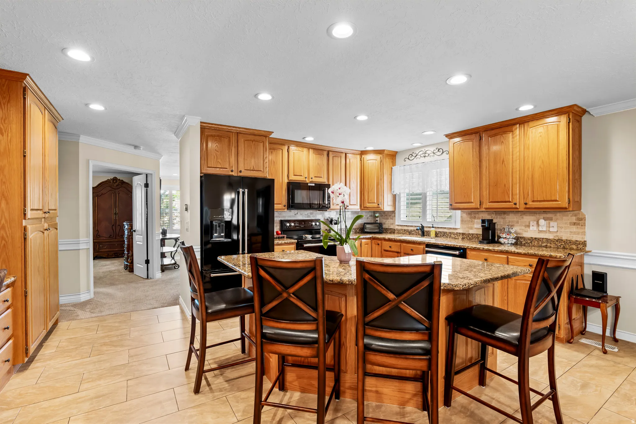 Spacious kitchen featuring an island with counter seating, wood cabinetry, recessed lighting, and tile flooring