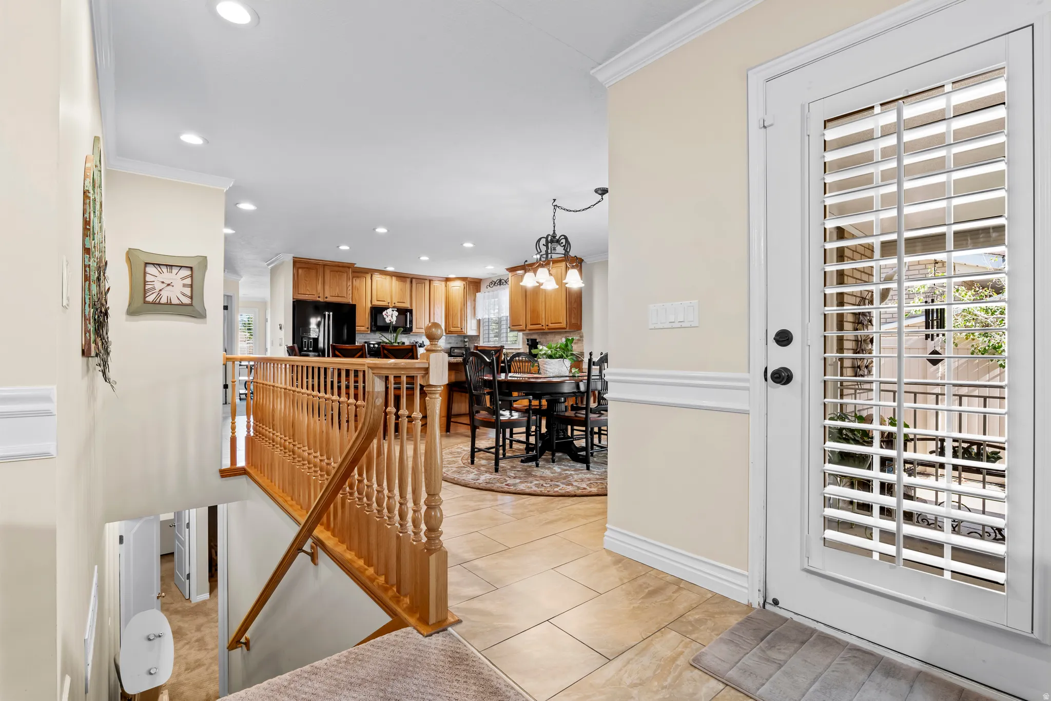 Entryway featuring a glass-paneled door with integrated blinds, ceramic tile flooring, and a wooden staircase with balusters