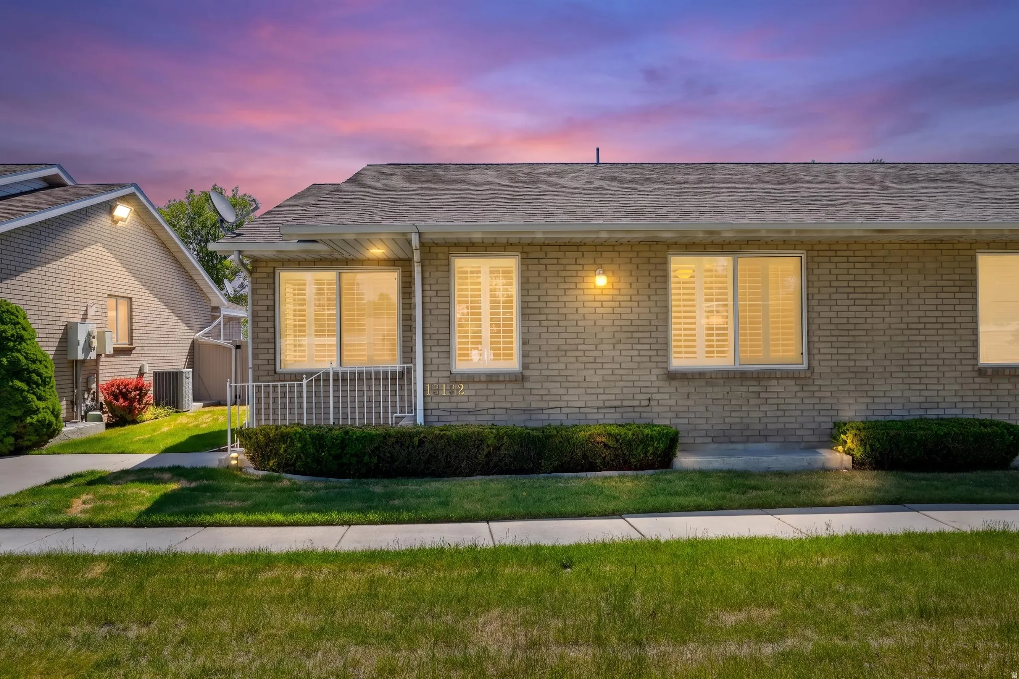 Brick exterior with a shingle roof and illuminated sconce lighting