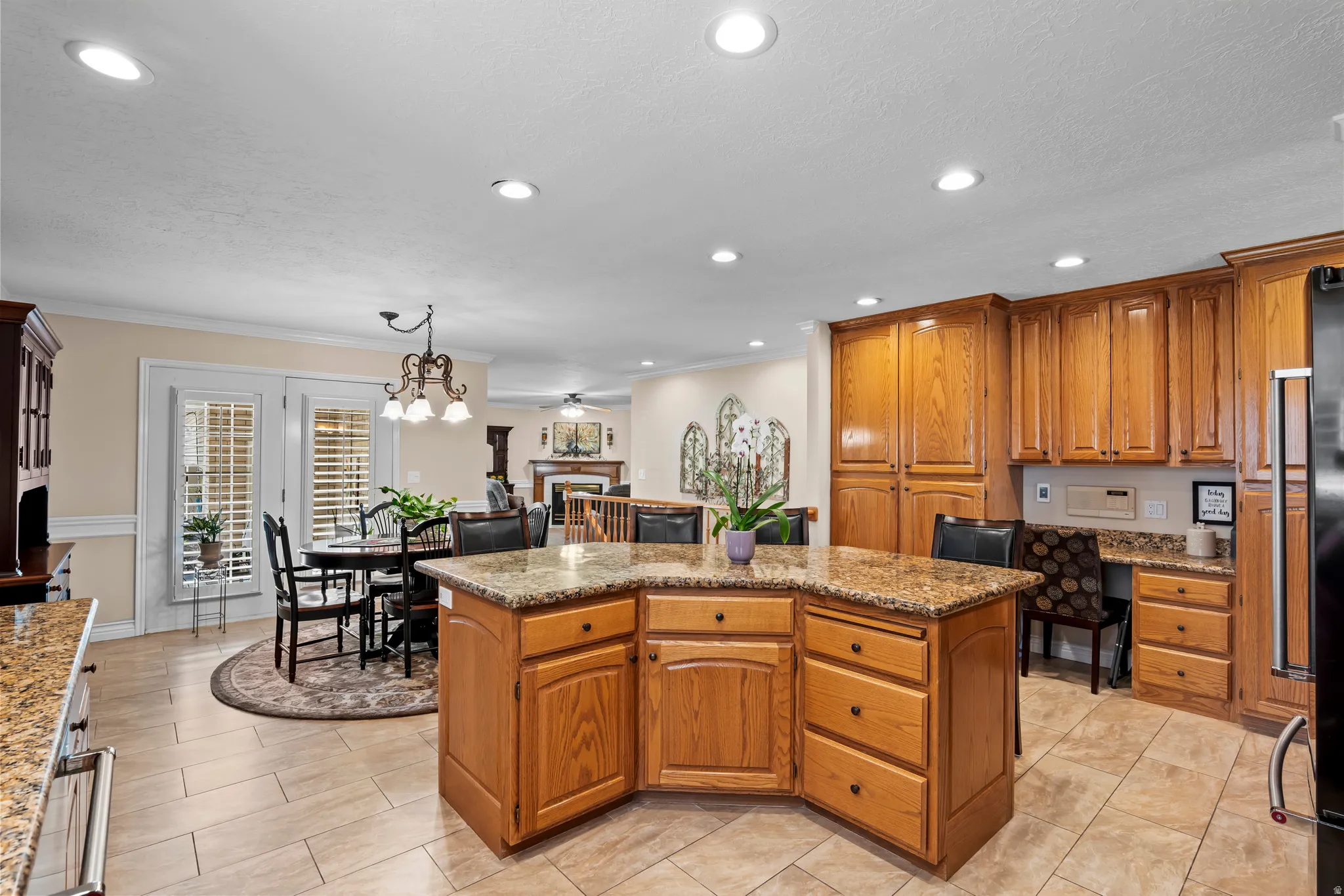 Kitchen featuring a multi-level island with stone-finish countertop, wood cabinetry, tile flooring, and recessed lighting
