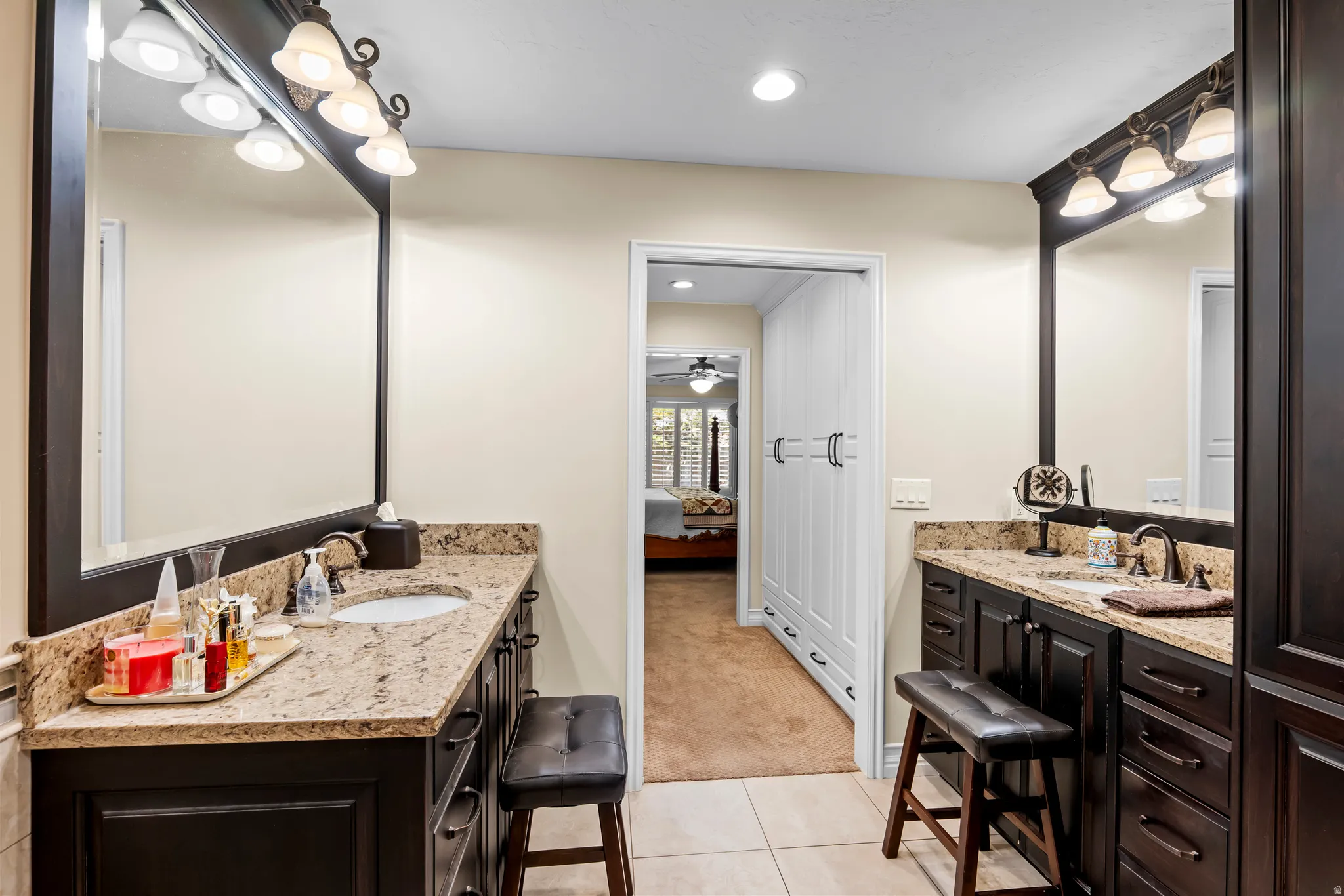 Bathroom featuring dual dark wood vanities with granite countertops and undermount sinks