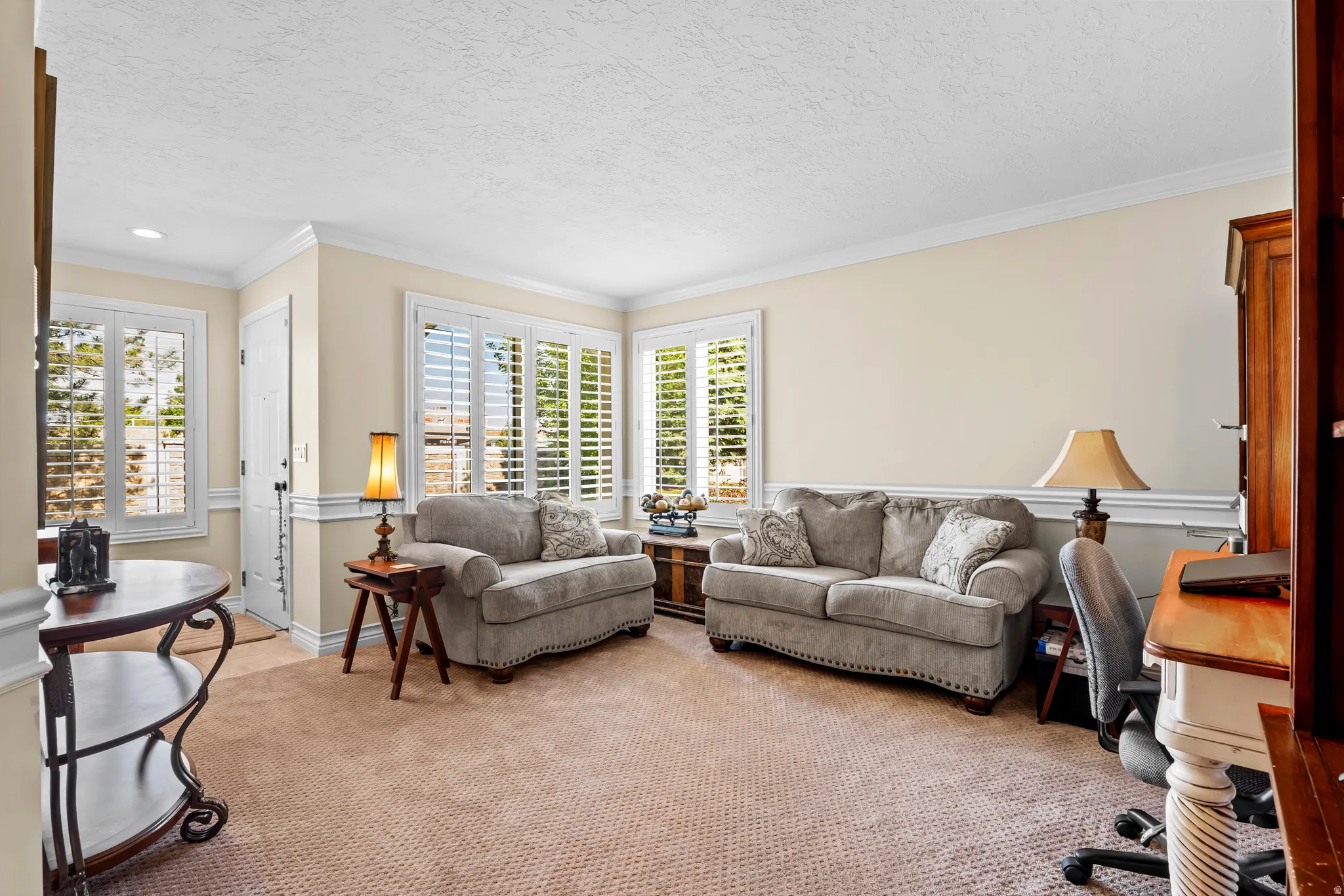 Carpeted interior space featuring neutral wall tones, white crown molding, and wainscoting