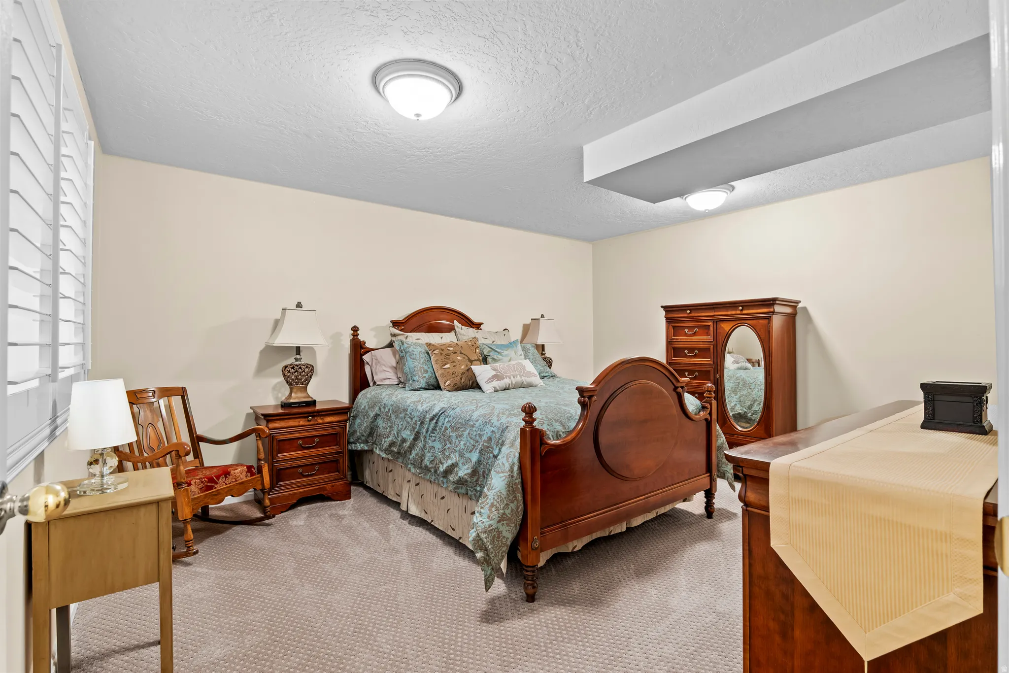 Carpeted bedroom featuring neutral wall tones and white plantation shutters