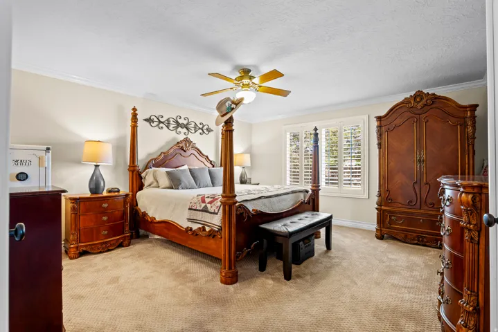 Spacious room featuring neutral carpeting, crown molding, and a ceiling fan with integrated lighting