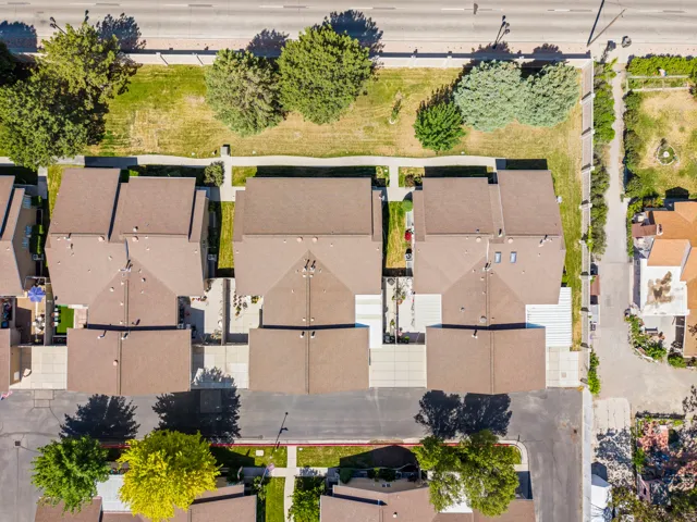 Aerial perspective showcasing a residential street with multiple properties, each featuring brown shingle roofing and individual concrete driveways