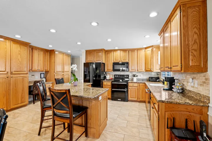 Spacious kitchen featuring extensive wood cabinetry, granite countertops, and a central island with seating