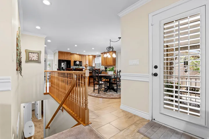 Entryway featuring a glass-paneled door with integrated blinds, ceramic tile flooring, and a wooden staircase with balusters