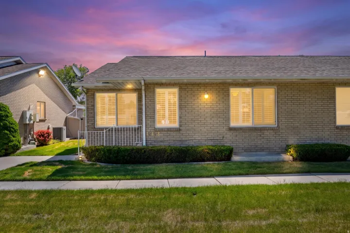 Brick exterior with a shingle roof and illuminated sconce lighting