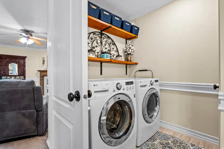 Dedicated laundry area with light-toned walls and wood-finish flooring