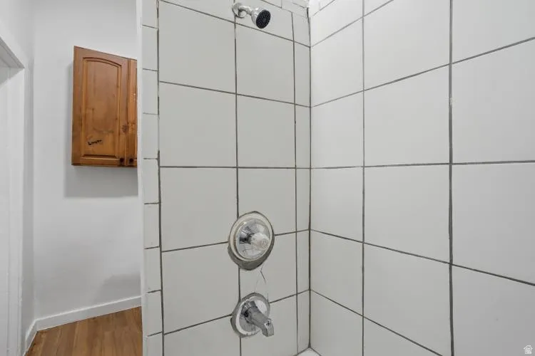 Shower enclosure with white square tiles and dark grout