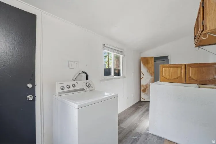 Utility room featuring wood-finish flooring and a window with blinds
