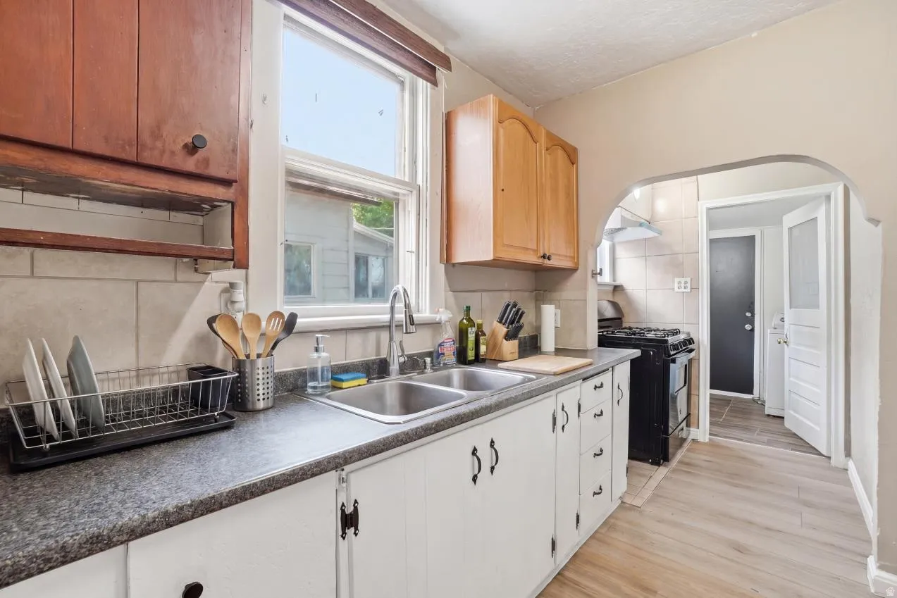 Kitchen featuring wood-finish flooring, a dual basin stainless steel sink, and a gas range