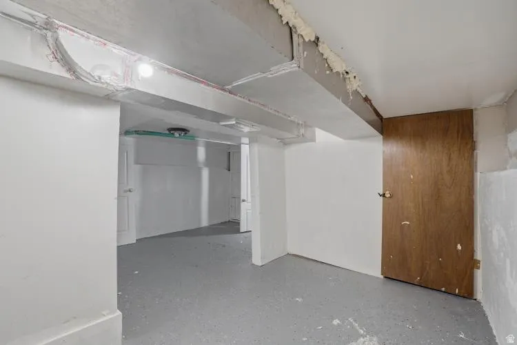 Unfinished interior space featuring a concrete floor, exposed ductwork, and white painted walls