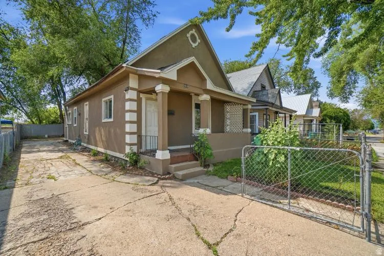 Stucco exterior residence featuring a covered front porch with decorative columns