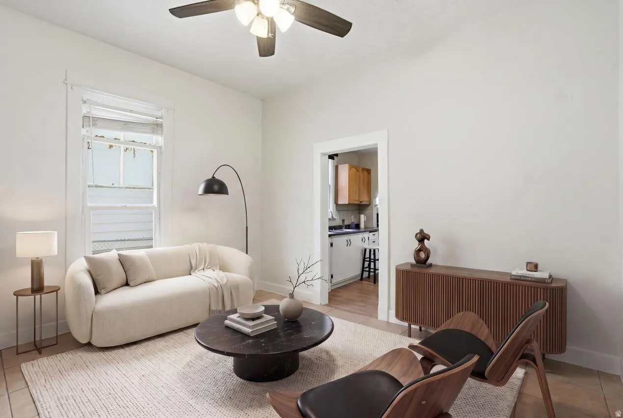 Bright living area featuring a ceiling fan with integrated lighting, wood-finish flooring, and white painted walls