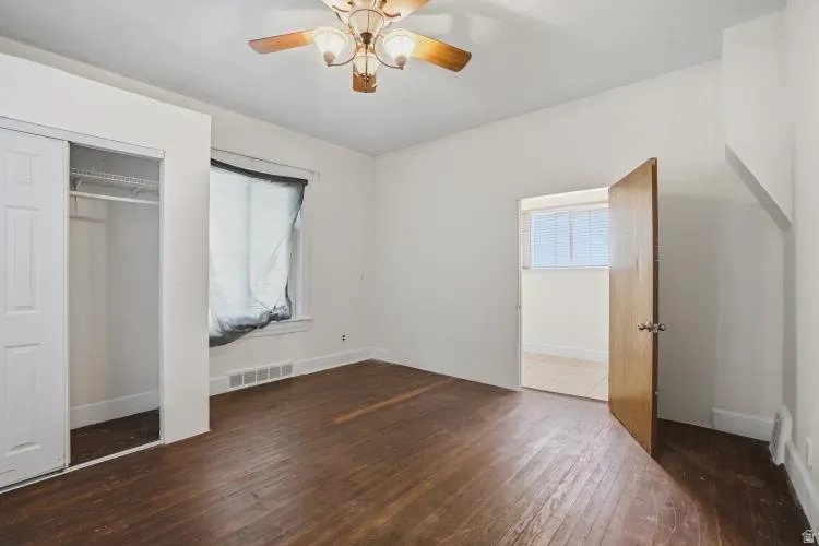 Room featuring wood-finish flooring, a ceiling fan with integrated lighting, and white baseboards