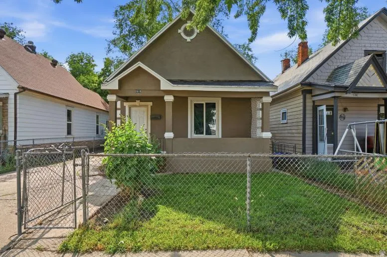 Stucco exterior featuring a covered front porch with column supports and a decorative gable vent