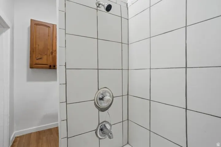Shower enclosure with white square tiles and dark grout