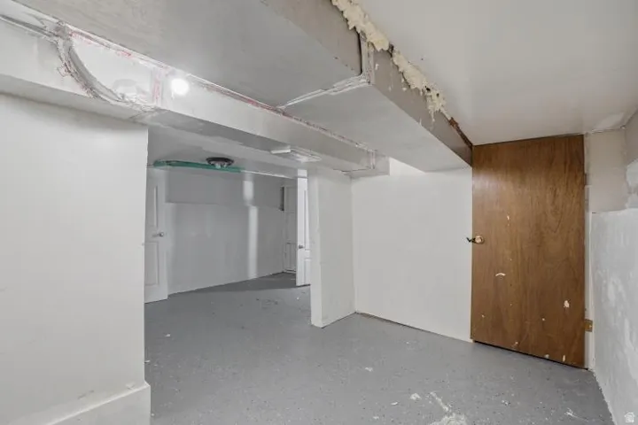 Unfinished interior space featuring a concrete floor, exposed ductwork, and white painted walls