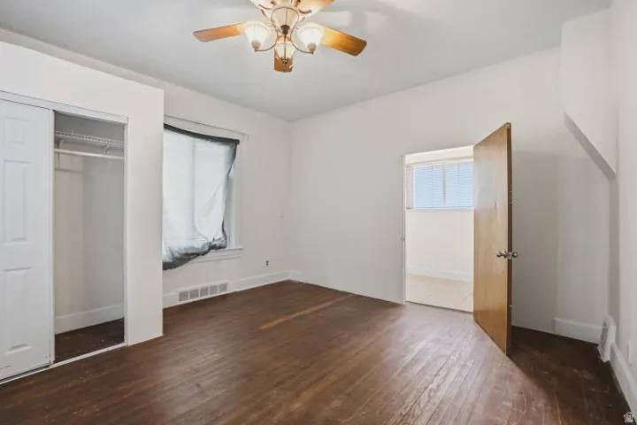 Room featuring wood-finish flooring, a ceiling fan with integrated lighting, and white baseboards
