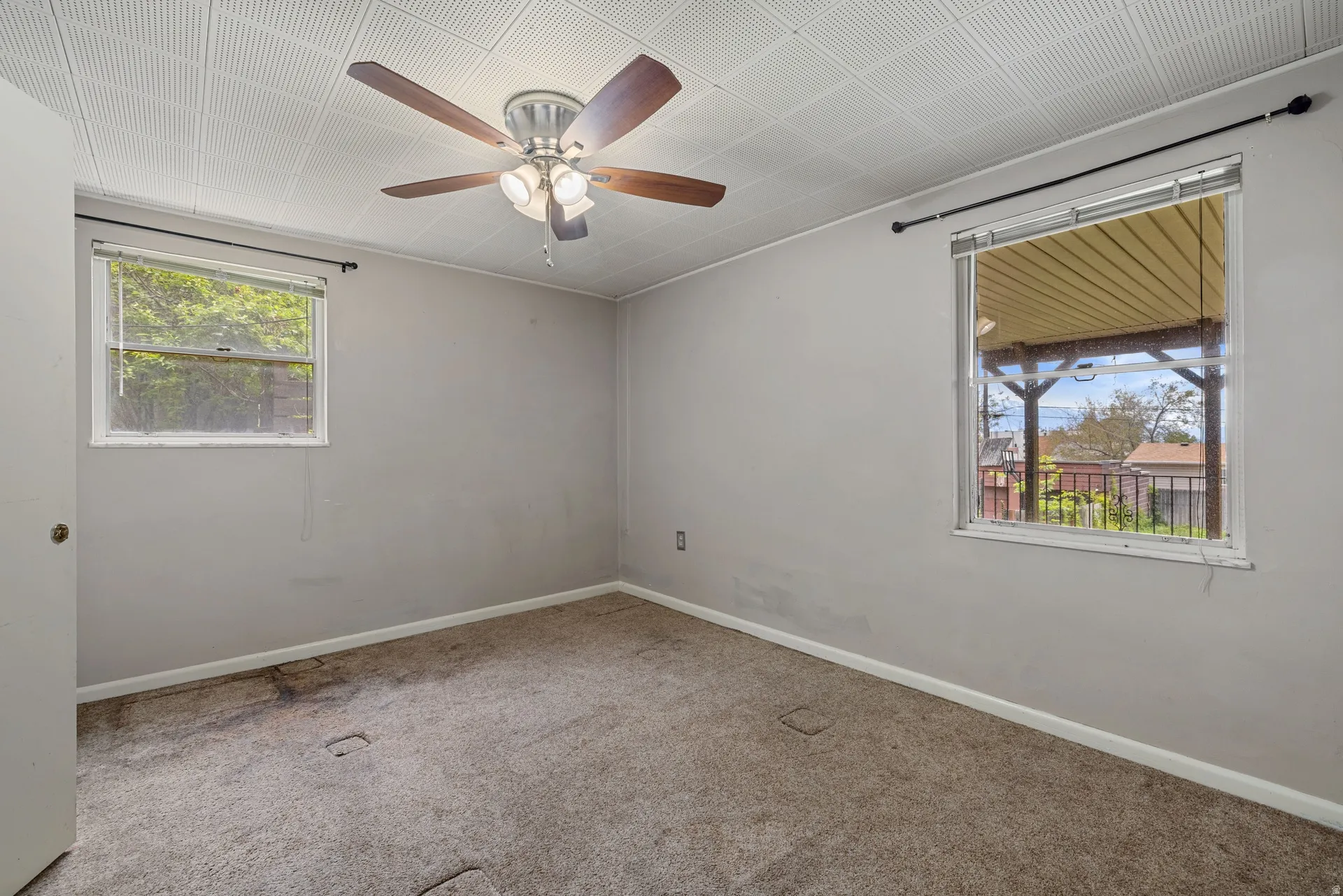 Bedroom featuring a ceiling fan with integrated lighting, two windows, and light gray wall paint