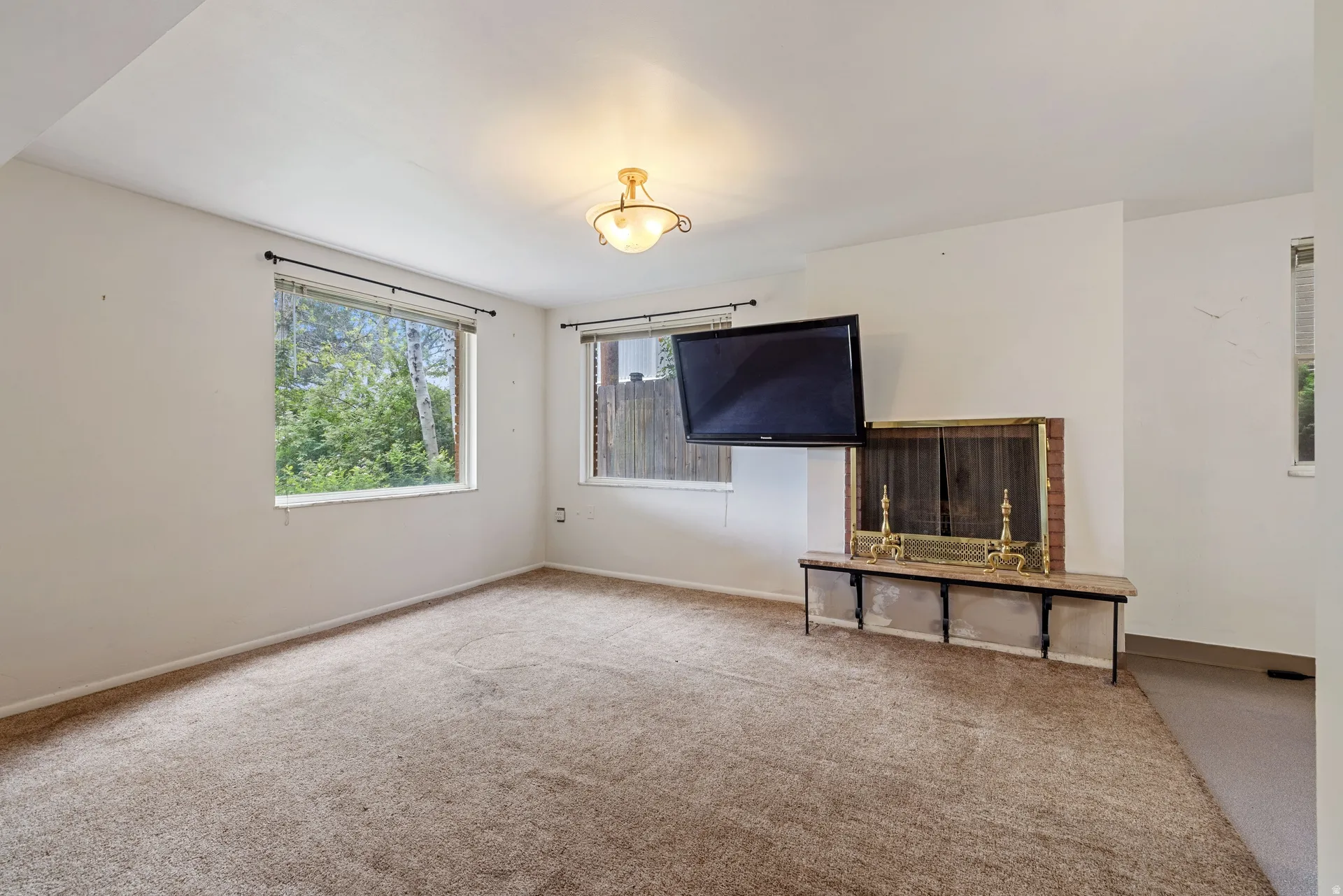 Carpeted room featuring a brick fireplace with a stone mantel