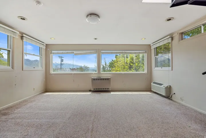 Carpeted room with multiple windows, recessed lighting, and wall-mounted heating/cooling units
