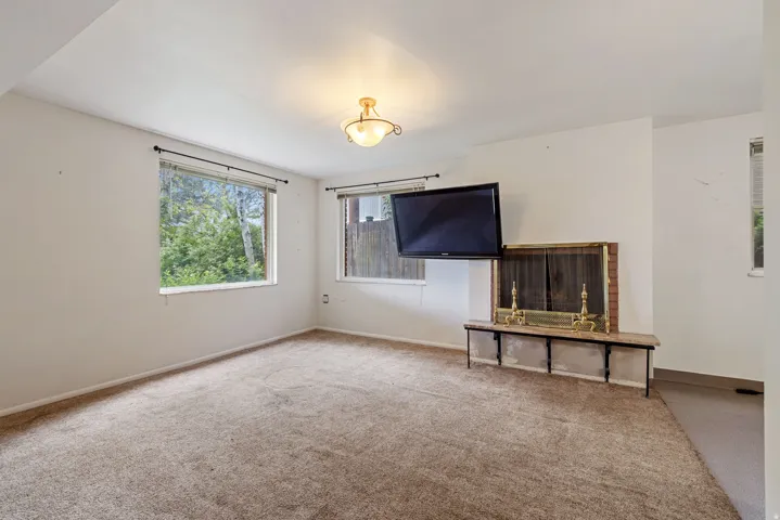 Carpeted room featuring a brick fireplace with a stone mantel