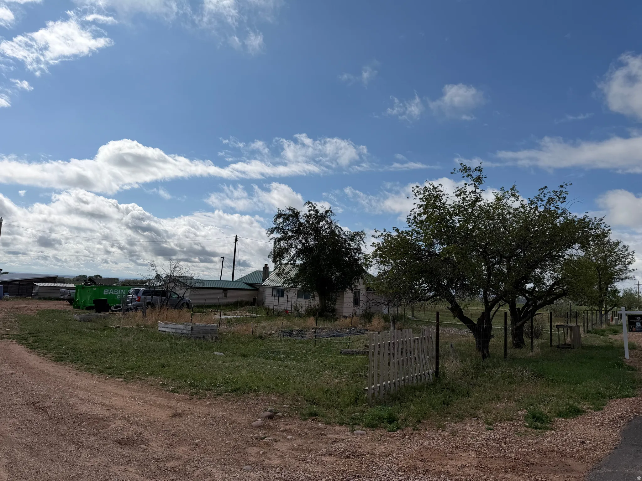 Expansive outdoor area featuring mature trees and a partial wood fence
