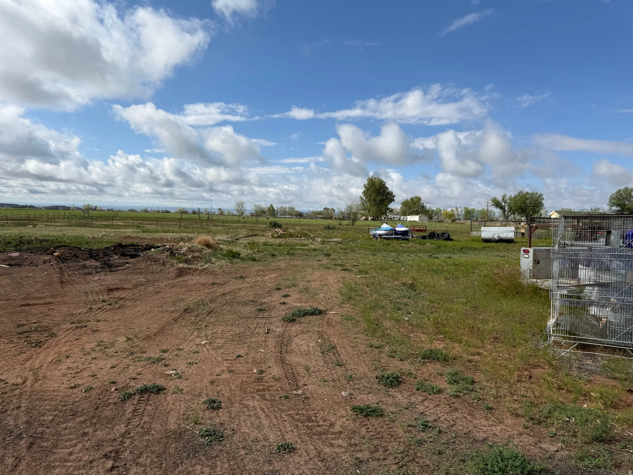 Expansive open land featuring a mix of cleared earth and natural grassland
