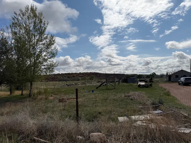 Rural landscape featuring expansive open space, distant hills, mature trees, and a gravel driveway leading to a structure